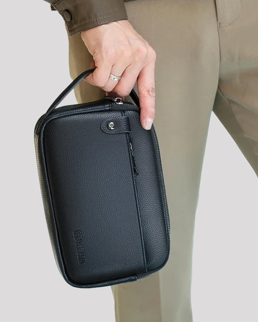 Man carrying black leather clutch bag vertically by top handle