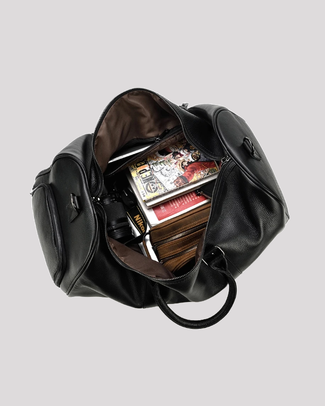 Black leather travel duffel bag open view – packed with books and camera