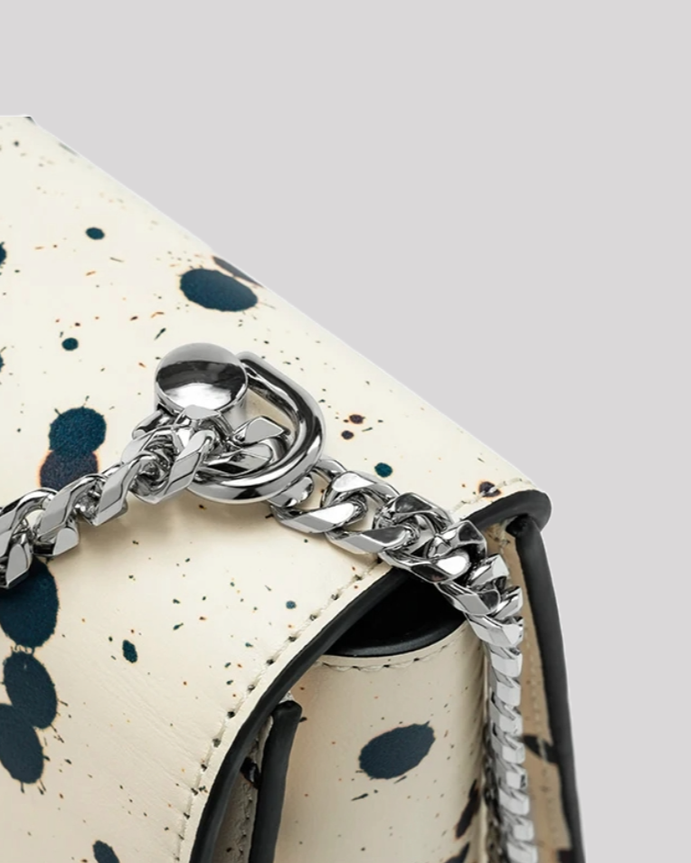 Close-up of silver chain strap attachment on black splatter paint shoulder bag by Bafelli