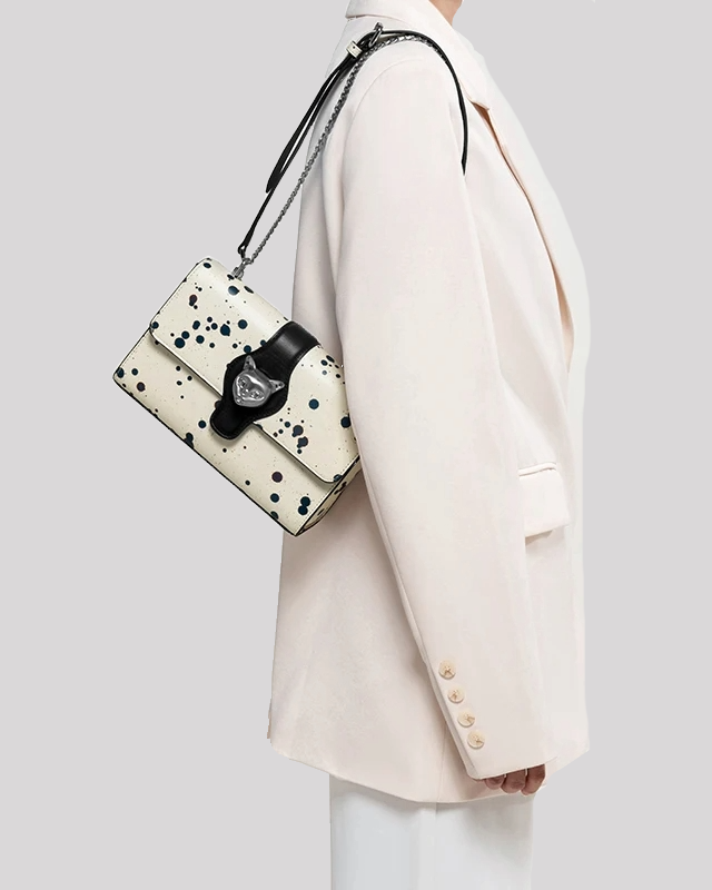 Model wearing black splatter paint shoulder bag with silver cat clasp and chain strap by Bafelli