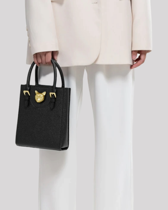 Model holding black tote bag by Bafelli with gold cat ornament, showing medium size and elegant proportions