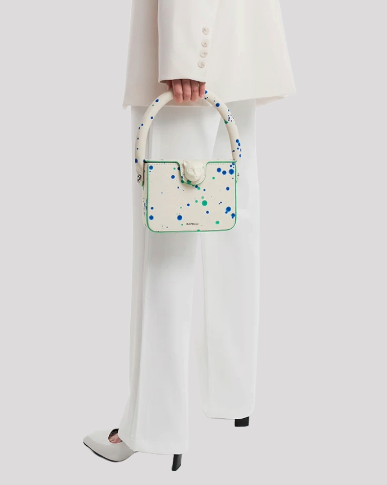 Woman carrying Blue Green Splatter Cat Bag by Bafelli with white suit – elegant lifestyle view