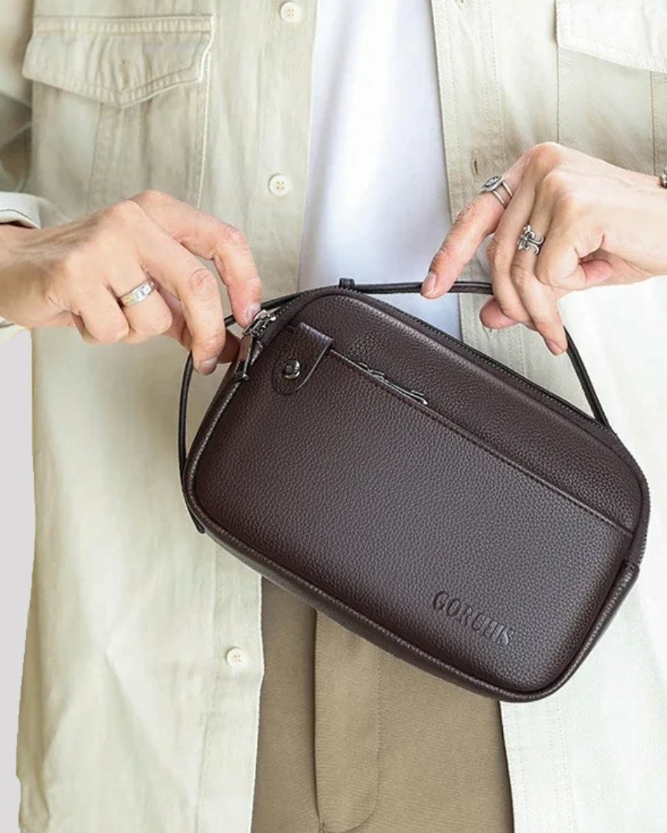 Man holding brown leather men’s handbag while opening zipper – casual outfit view