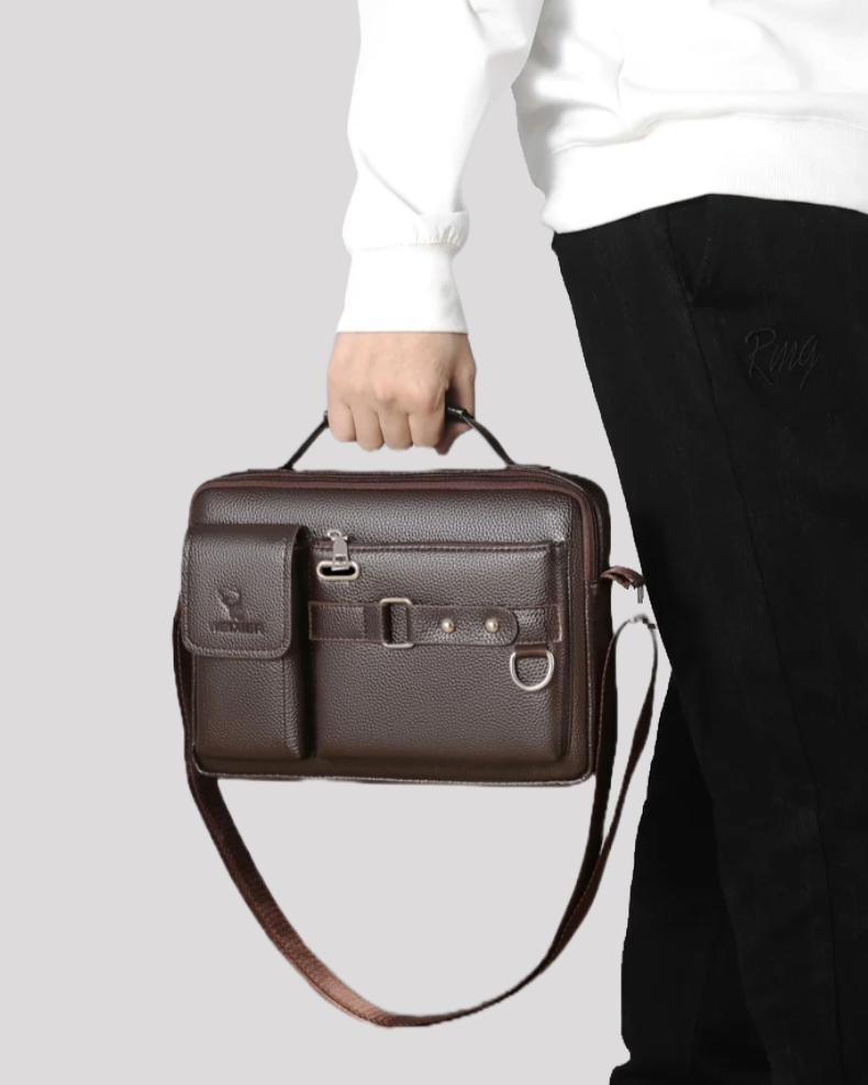 Man holding brown leather messenger bag by top handle – casual outfit view