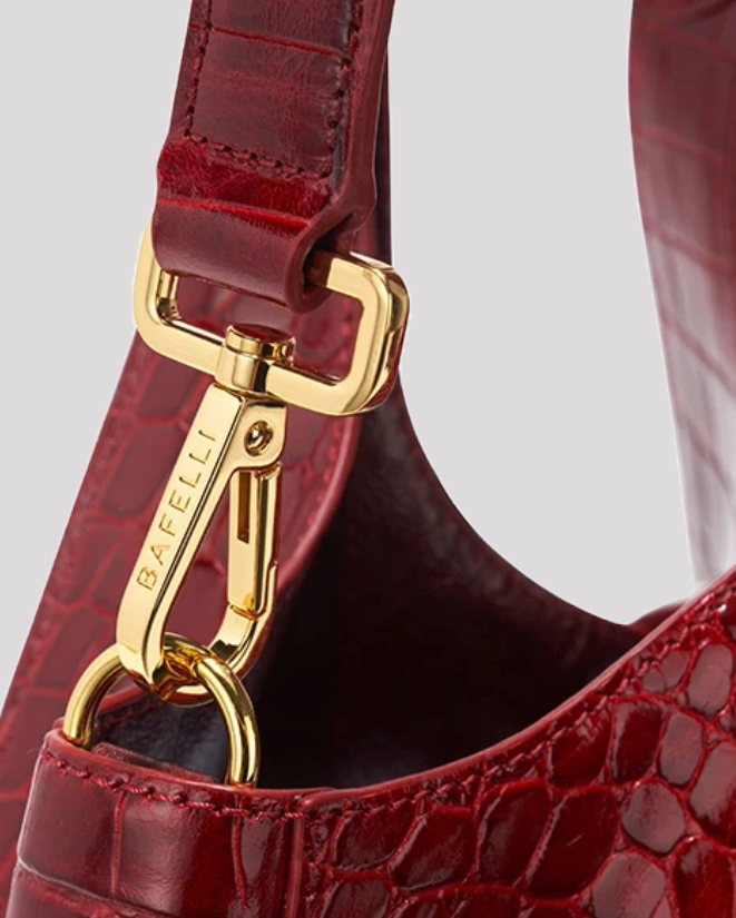 Close-up of gold hardware clip on burgundy croc tote bag by Bafelli with brand engraving