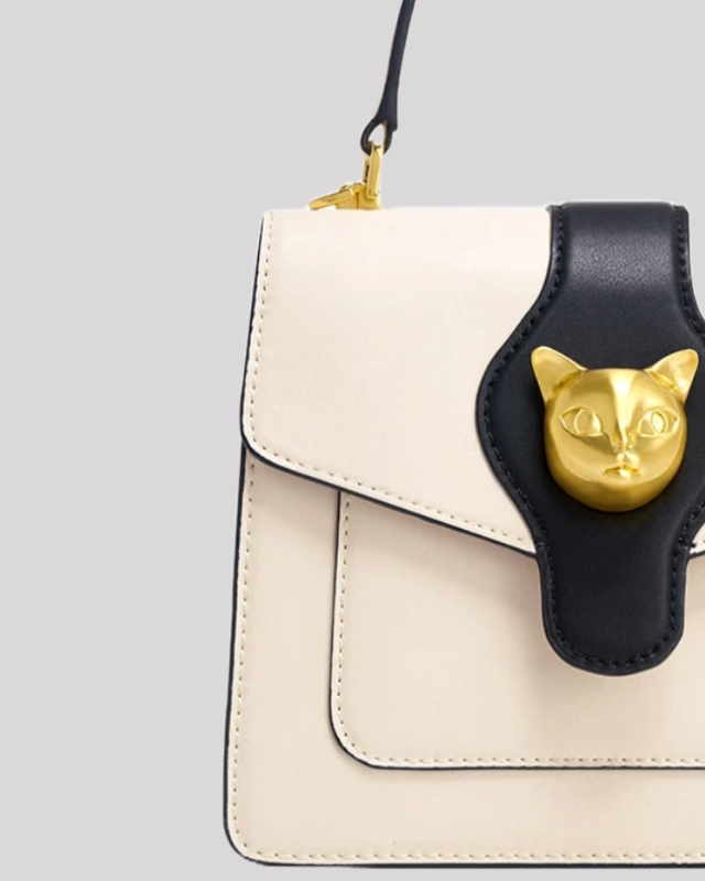 Close-up of cream and black handle bag by Bafelli highlighting gold cat head clasp and fine stitching