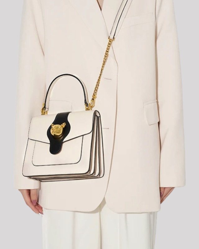 Cream and black handle bag by Bafelli worn on shoulder with gold chain strap for versatile styling