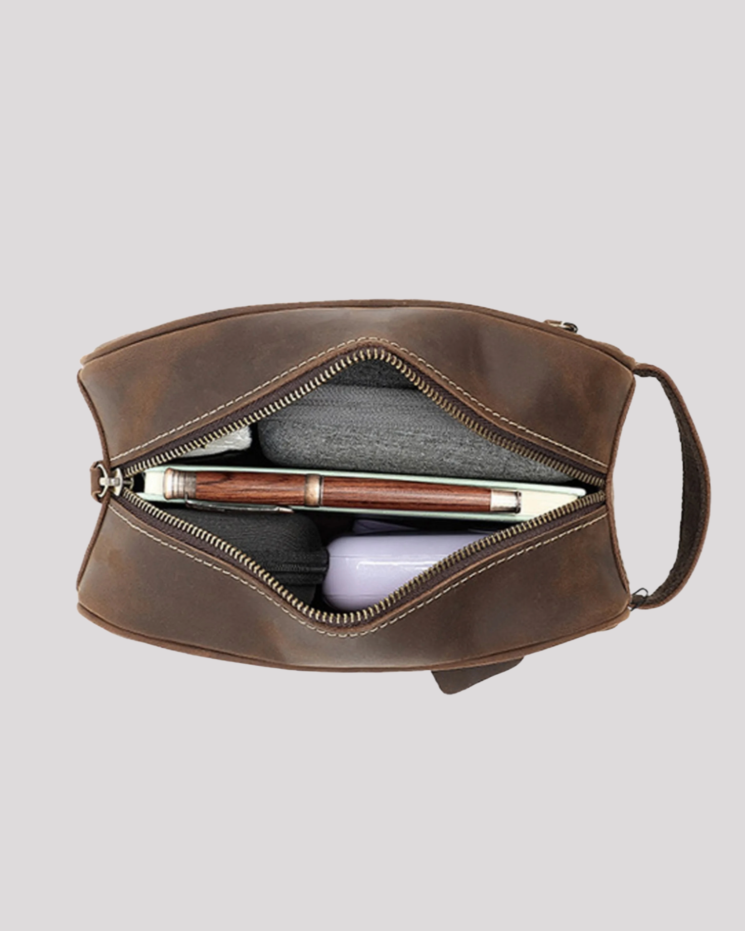 Open view of dark brown leather toiletry bag showing spacious interior with accessories inside