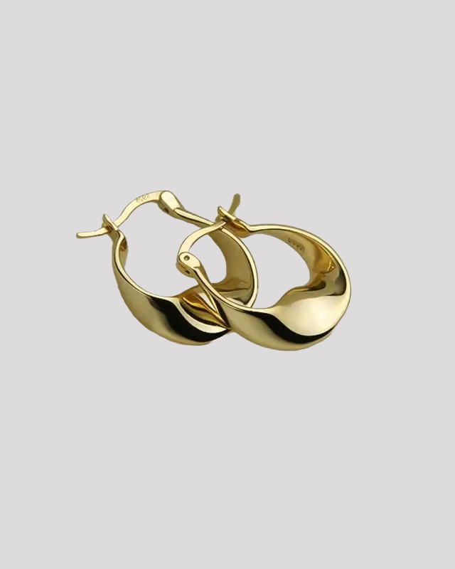 Gold wavy hoop earrings – close-up on gray background