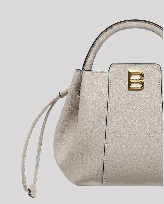 Close-up of gray textured leather bucket bag by Bafelli showing grainy leather texture and gold B logo detail
