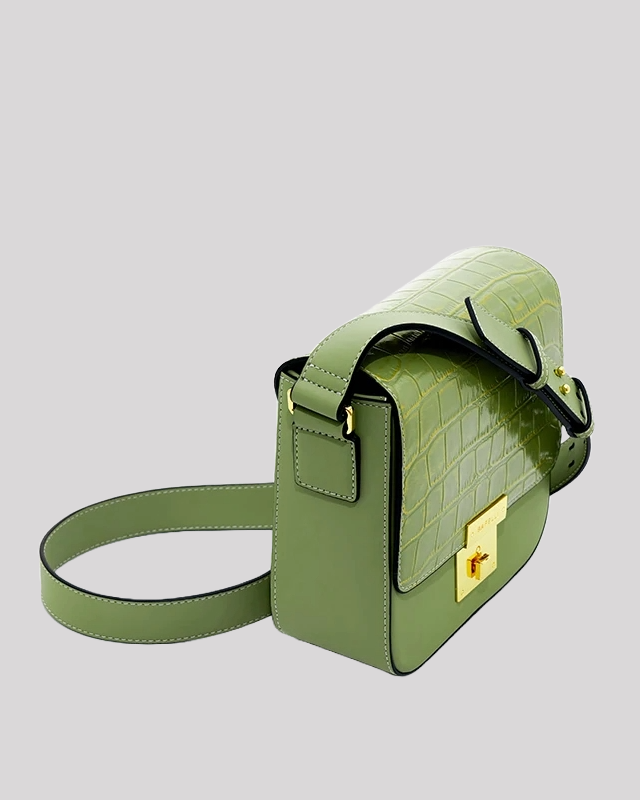 Side angle view of green croc-embossed shoulder bag by Bafelli highlighting gold hardware and wide strap