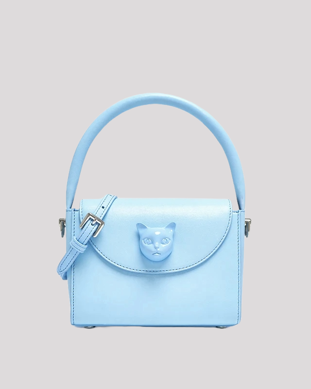Front view of light blue handbag by Bafelli with cat face embellishment and top handle
