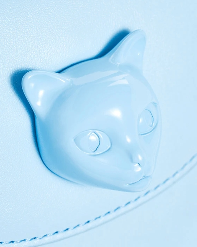 Close-up of cat face embellishment on light blue handbag by Bafelli flap