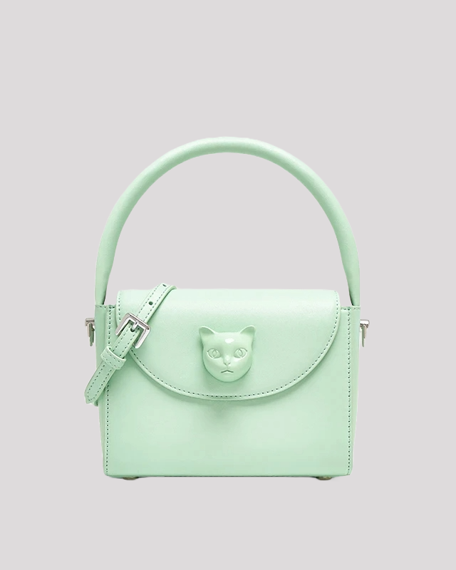 Front view of mint green handbag by Bafelli with structured handle, flap closure, and embossed cat face detail