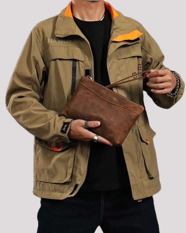 Man carrying mocha leather clutch bag by wrist strap – casual outfit view