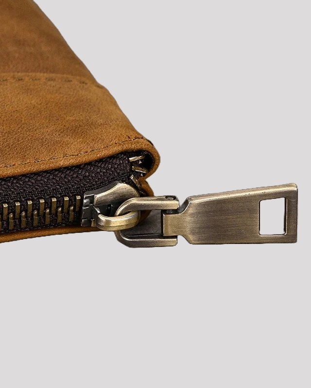Close-up detail of mocha leather clutch bag zipper and metal puller