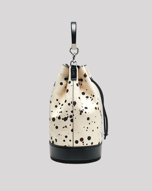 Interior view of cream bucket bag by Bafelli with black paint splatter, showing spacious compartment and drawstring closure