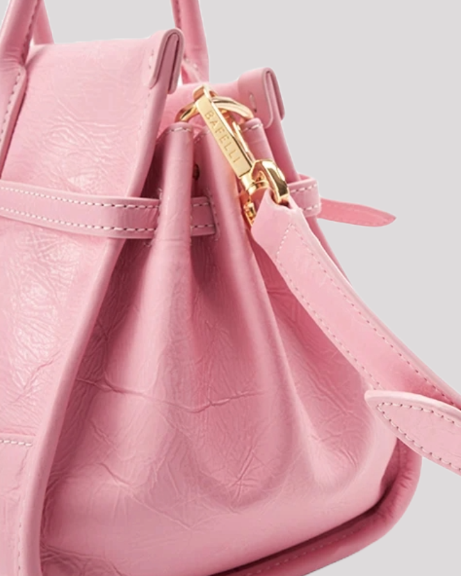 Side detail of pink leather shoulder bag by Bafelli with gold clasp and belt strap