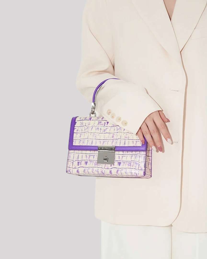 Woman in beige blazer holding purple croc-embossed handbag by Bafelli by top handle – lifestyle view