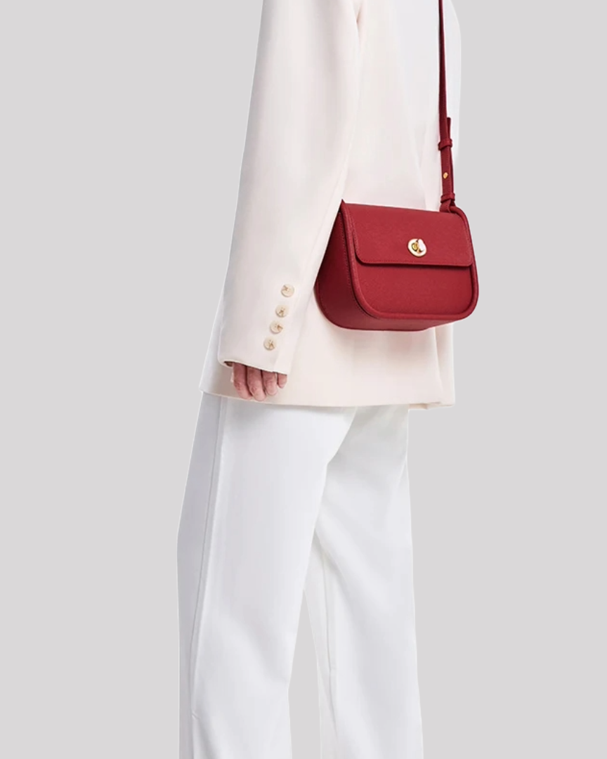 Red crossbody bag by Bafelli worn over the shoulder, styled with a white blazer and trousers