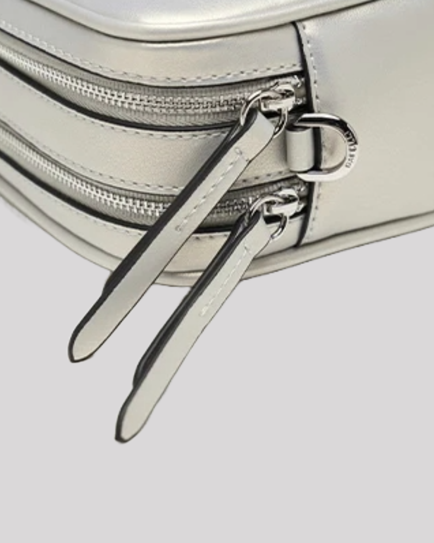 Close-up of silver crossbody bag by Bafelli dual zipper pulls with leather tags and metal hardware