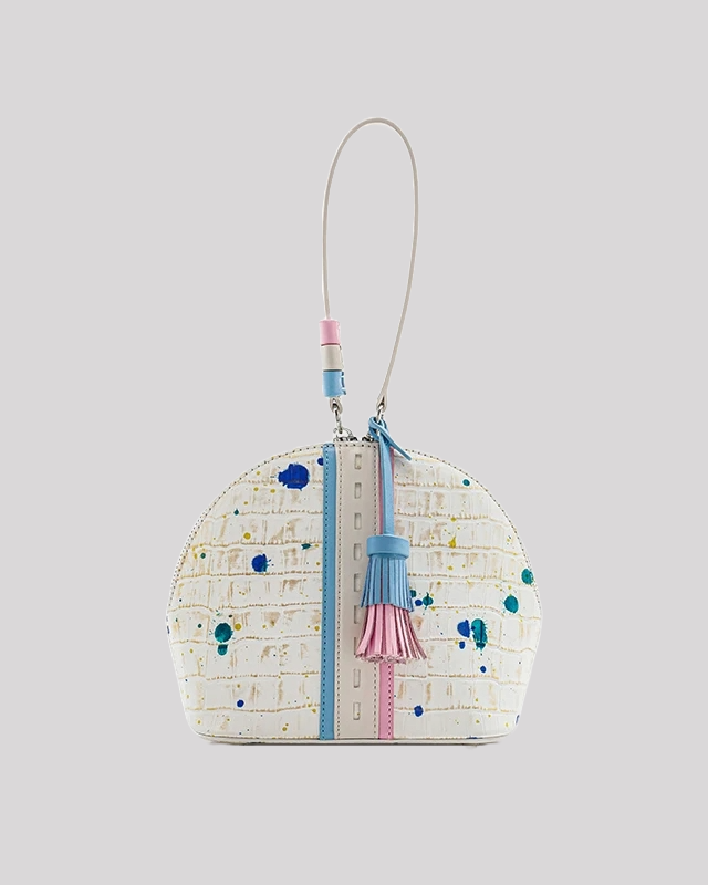 Front view of white crocodile-embossed wristlet bag by Bafelli with colorful paint splatter, blue and pink tassel detail, and zip closure