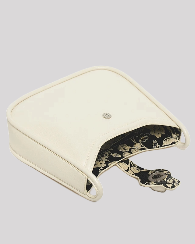 Interior view of white leather shoulder bag with floral lining and magnetic closure