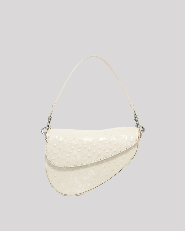 Front view of white ostrich-embossed asymmetric shoulder bag by Bafelli with curved flap and top handle