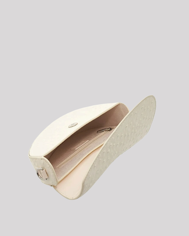 Interior view of white ostrich-embossed asymmetric shoulder bag by Bafelli with beige lining and zipper pocket