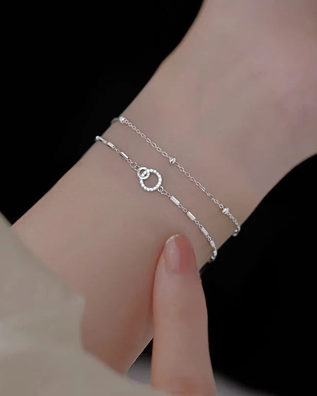 Close-up of women’s delicate silver bracelet with heart and circle pendant, fine chain design