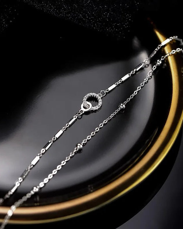 Women’s silver bracelet with heart and circle charm – product detail view on dark background