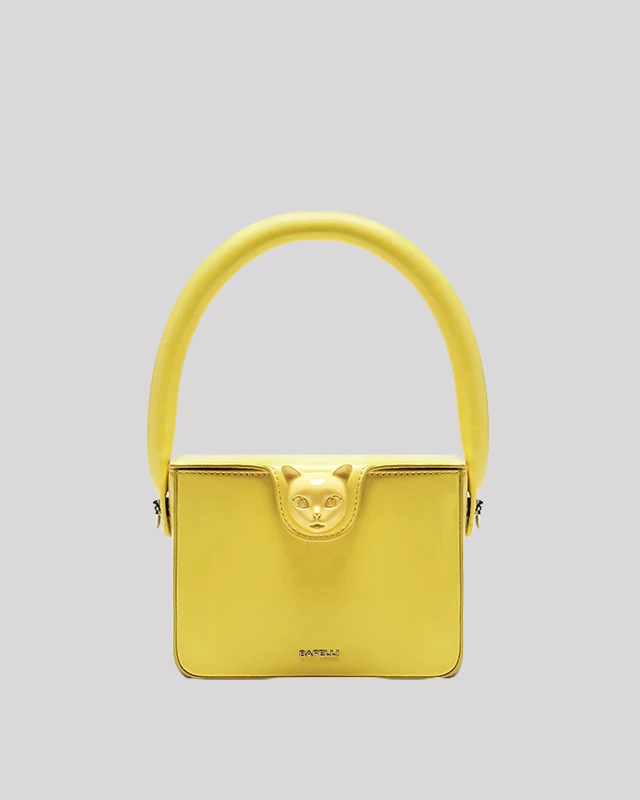 Front view of yellow top handle bag by Bafelli with cat head clasp and structured design