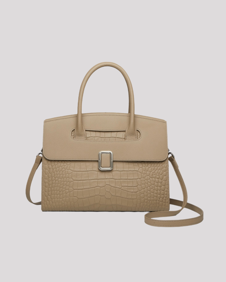 Front view of beige croc-embossed leather handbag with top handle, silver buckle detail and detachable shoulder strap