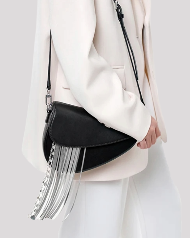 Model wearing black asymmetric shoulder bag by Bafelli with silver fringe chain detail over the shoulder