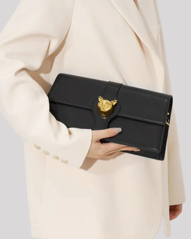 Model holding black cat-emblem shoulder bag by Bafelli in hand, styled with white blazer for elegant look