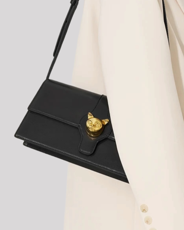 Black cat-emblem shoulder bag by Bafelli worn on the shoulder with gold hardware and slim strap