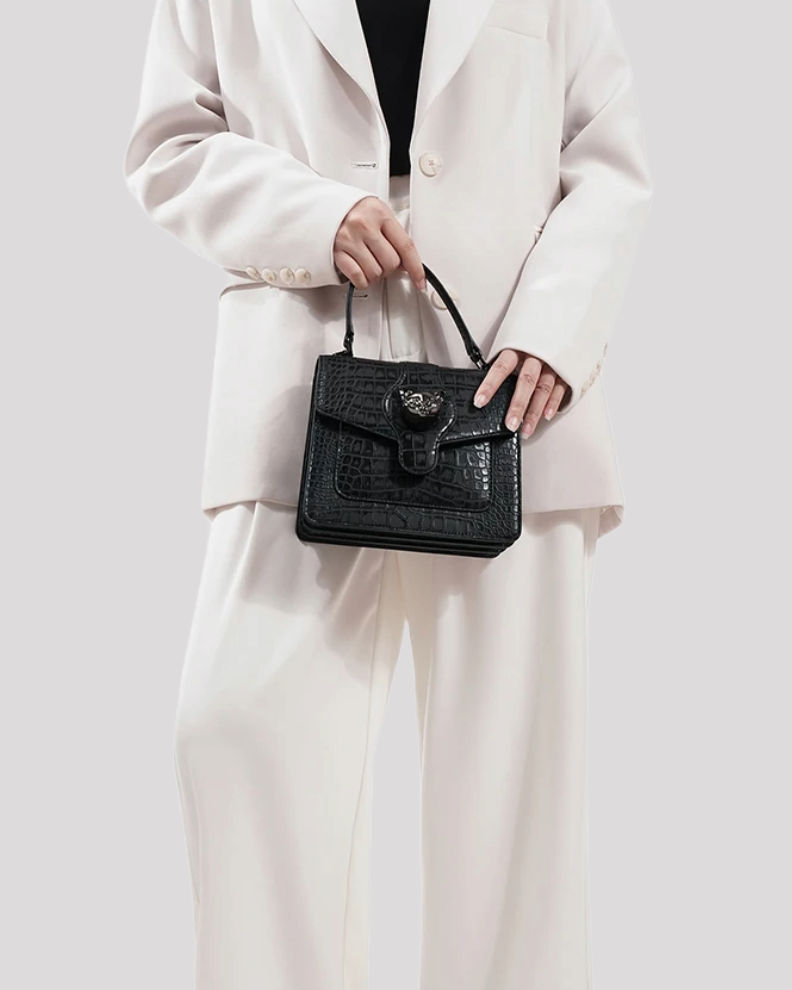 Woman in white suit holding black croc-embossed leather handbag by Bafelli with top handle – lifestyle view