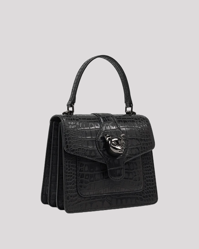 Side angle of black croc-embossed leather handbag by Bafelli with structured shape and cat head clasp