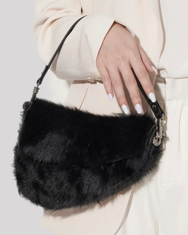 Woman holding black faux fur shoulder bag by Bafelli in hand, styled with cream blazer