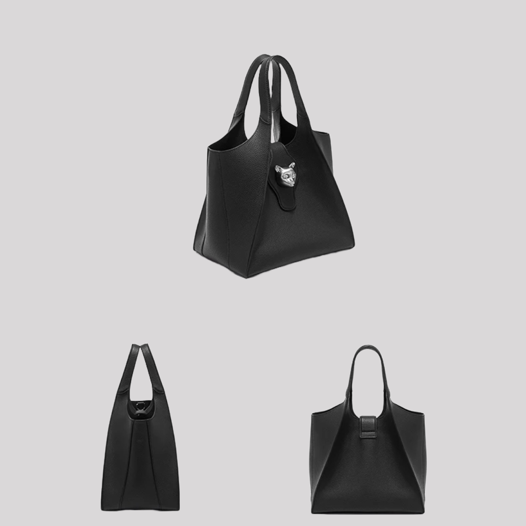 Angled side view of black leather tote bag by Bafelli with textured finish and silver cat emblem clasp