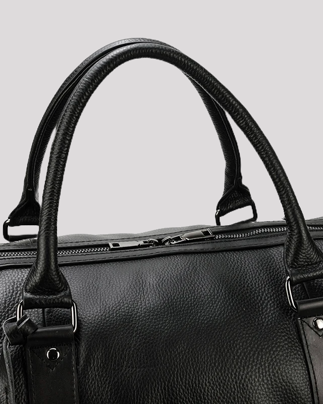 Reinforced handle detail of black leather travel duffel bag with stitching
