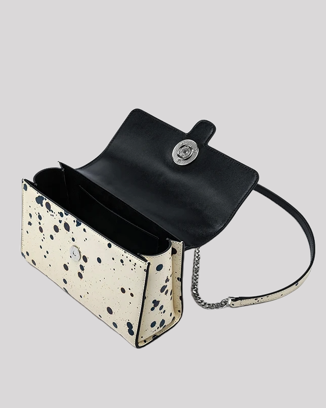 Open view of black splatter paint shoulder bag with black leather interior and compartments by Bafelli