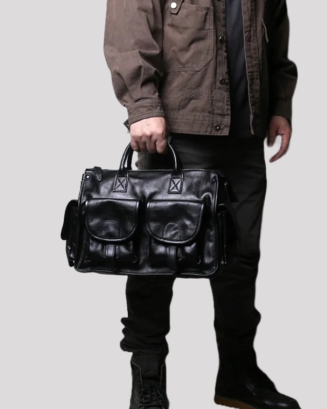 Black vintage leather messenger bag carried by a person, showing scale and structured design