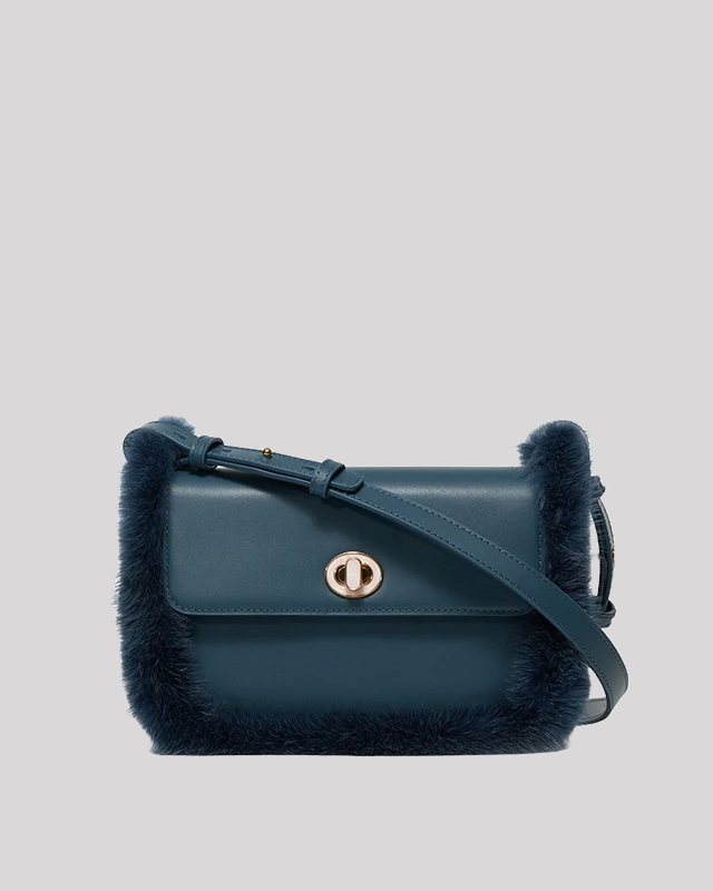 Front view of blue fur-trim crossbody bag by Bafelli with smooth leather body, soft faux fur edges, and gold turn-lock closure