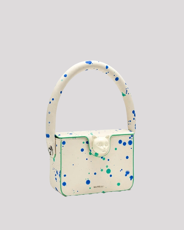 Side angle of Blue Green Splatter Cat Bag by Bafelli with round top handle and colorful splatter design