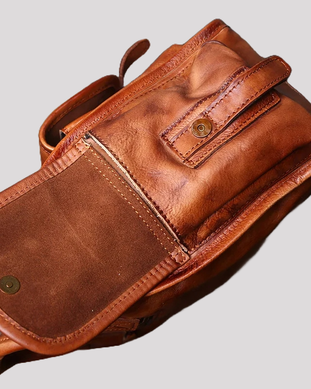 Open front pocket of brown vintage leather messenger bag showing suede lining and magnetic closure