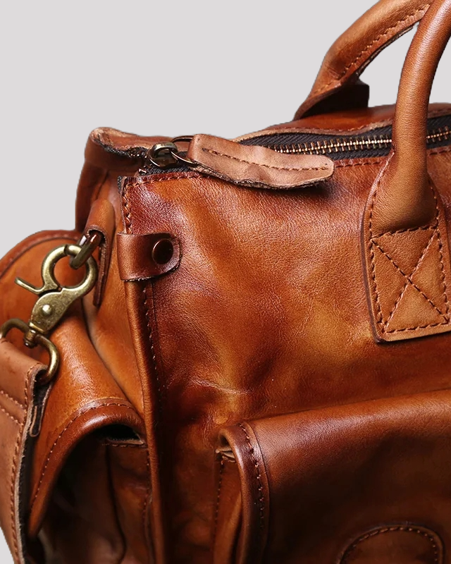 Side detail of brown vintage leather messenger bag highlighting brass hardware and stitching