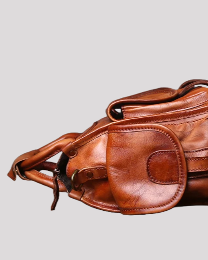 Side profile of brown vintage leather messenger bag with rounded pocket and strap attachment