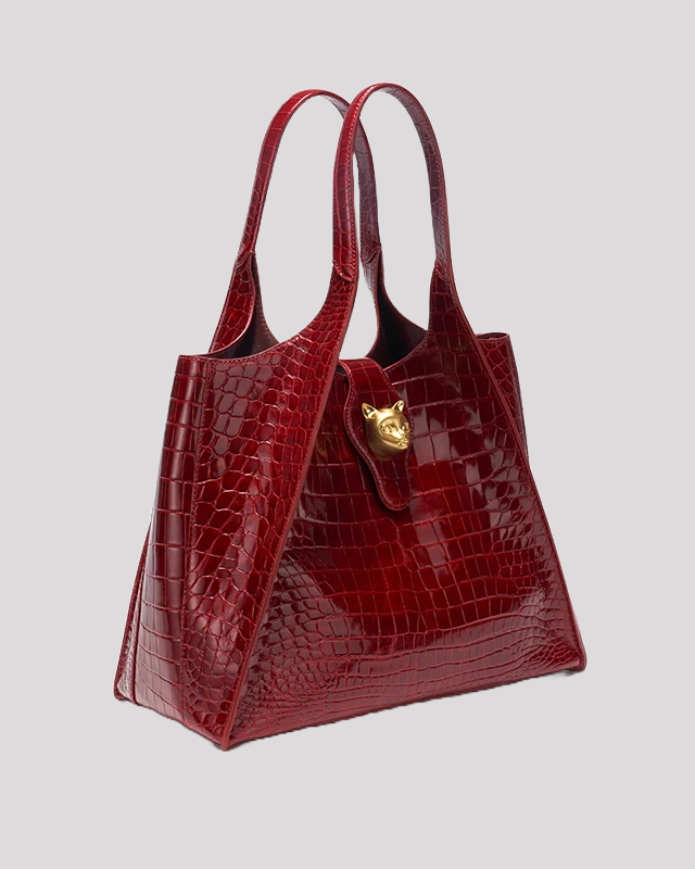Side angle of burgundy crocodile embossed tote bag by Bafelli showing structured silhouette and gold cat lock