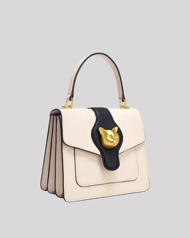 Side angle view of cream and black handle bag by Bafelli with layered structure and gold cat head detail
